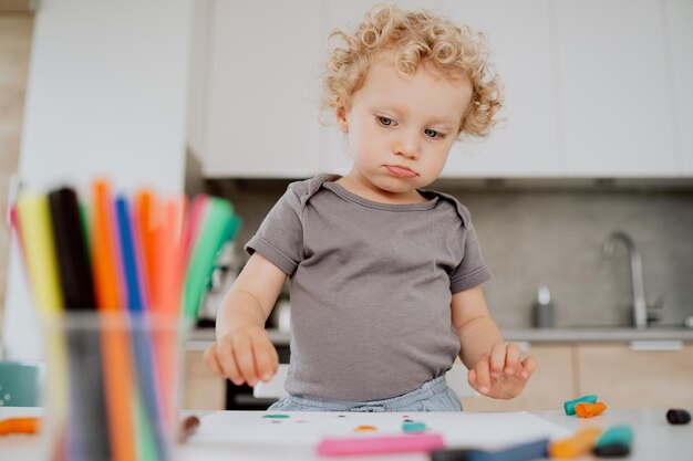 Portrait of a preschool girl sitting at her kitchen table playing with plasticine