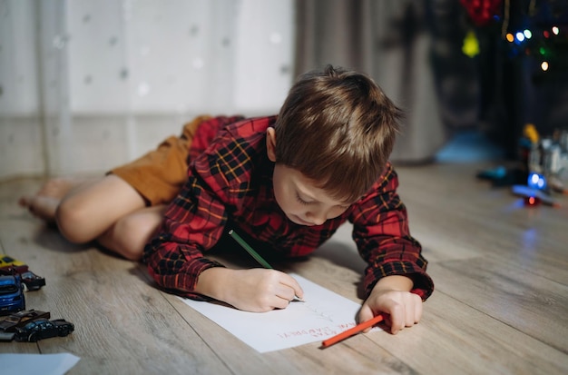 サンタにクリスマスの手紙を書いて床に敷設格子縞のシャツの未就学児の男の子の肖像画