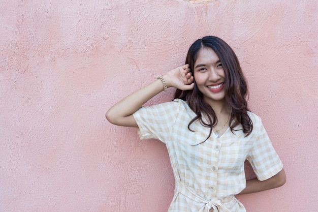 Portrait of a pretty Asian woman with a pink wall