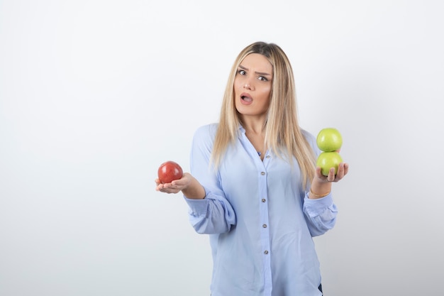 Portrait of a pretty attractive woman model standing and holding fresh apples .