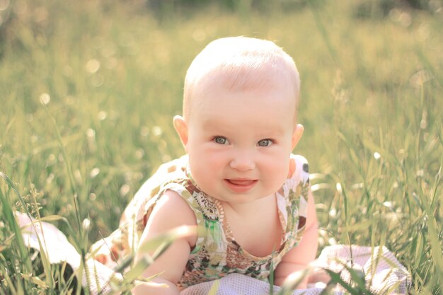 Photo portrait of pretty baby on the lawn on a summer day