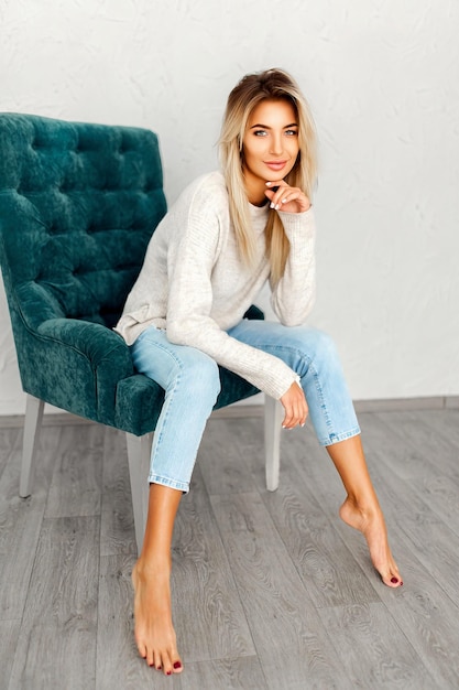 Portrait of pretty blonde woman sits on a chair Studio shot