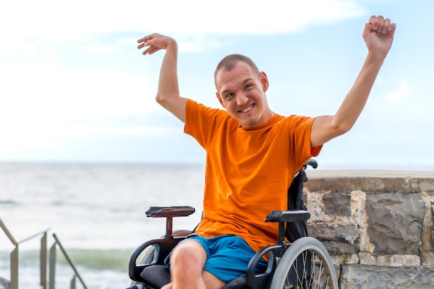 Portrait of pretty cheerful disabled person in wheelchair at the beach in summer vacation