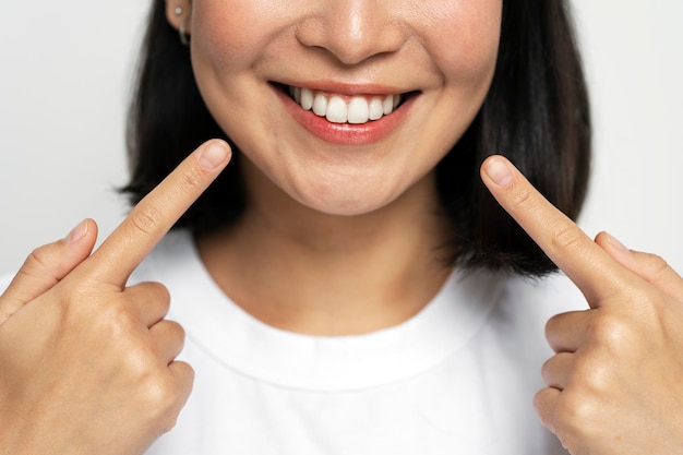 Portrait of pretty cheerful woman points index fingers at smile shows white teeth