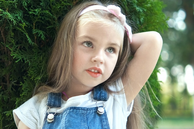 Portrait of pretty child girl standing outdoors in summer park.