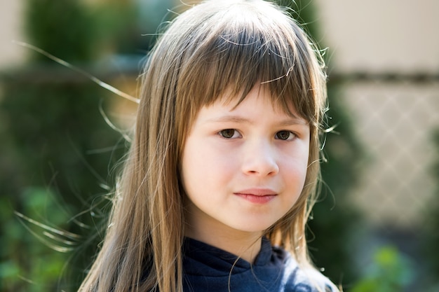 Portrait of pretty child girl with gray eyes and long fair hair outdoors on blurred bright surface