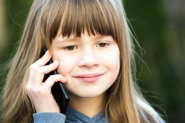 Portrait of pretty child girl with long hair talking on cell phone.