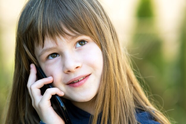 Ritratto di una bella bambina con i capelli lunghi che parla al cellulare.