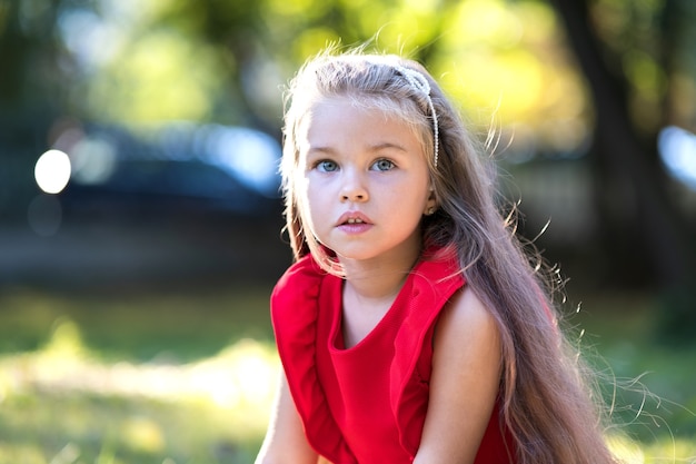 Portrait of pretty fashionable child girl in red dress enjoying warm sunny summer day.