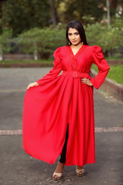 Portrait of pretty fashionable girl wearing red long dress with stylish pose