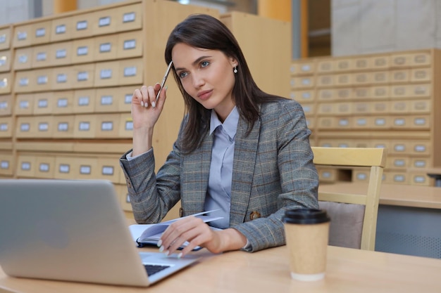 Portrait of a pretty female student with laptop in library
