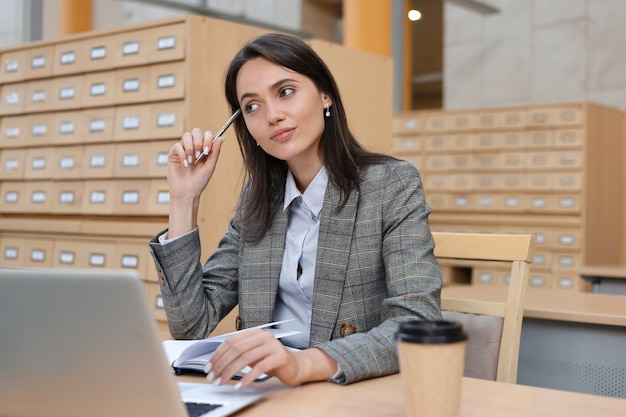 Portrait of a pretty female student with laptop in library.