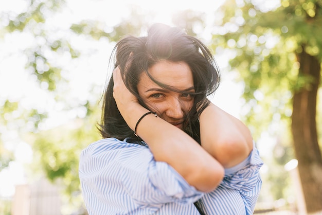 Portrait of pretty girl dressed in trendy clothes smiling broadly enjoying nice weather while relaxing at outdoor on sunny day People and lifestyle Youth fun and happiness concept