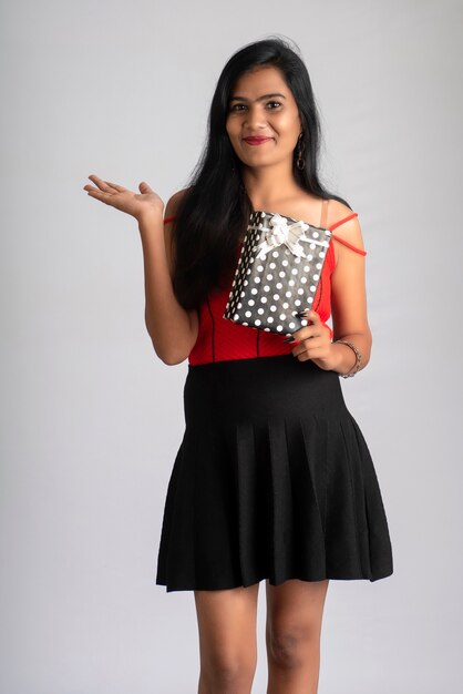 Portrait of a pretty girl holding and posing with a gift box.