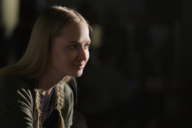 Portrait of pretty girl sitting in dark room in profile