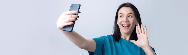 Photo portrait of a pretty girl taking a selfie isolated over grey background
