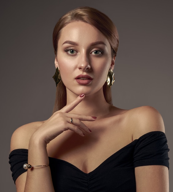 Portrait of pretty girl with natural make up wearing black off shoulders dress and touching face
