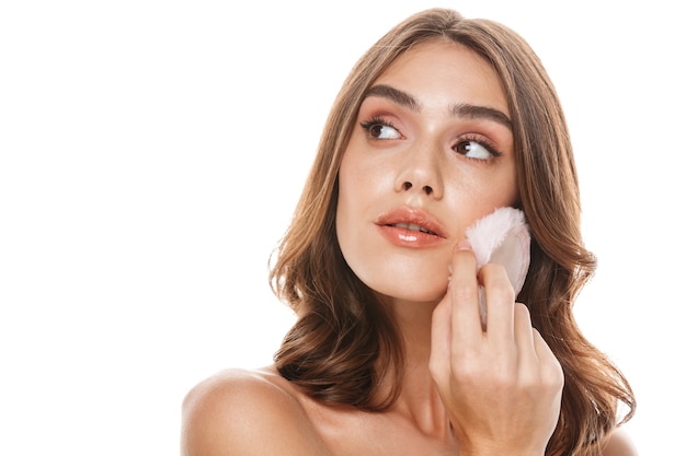 Portrait of pretty half-naked woman applying makeup with powder puff 