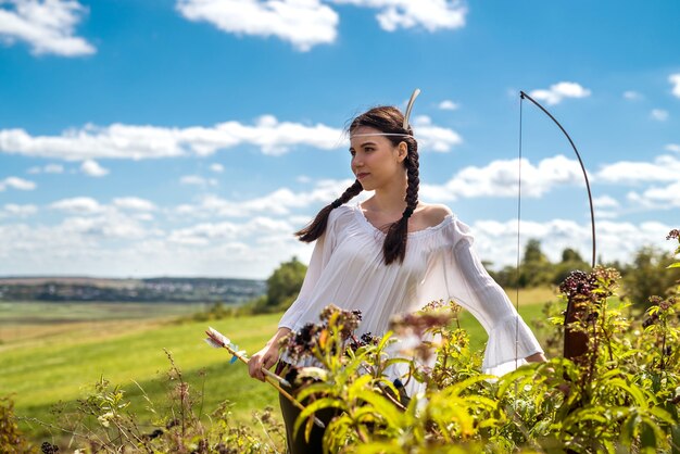 Il ritratto della donna abbastanza indiana posa in una natura che circonda. cacciatore femminile nativo americano all'aperto