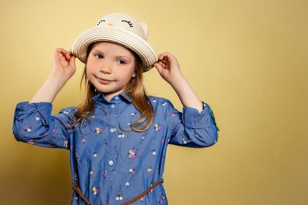 Portrait of pretty little girl in blue dress and yellow hat