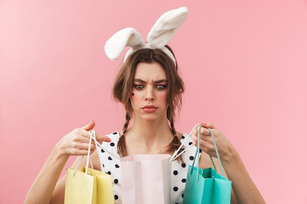 Portrait of a pretty lovely girl wearing bunny ears standing isolated, carrying shopping bags