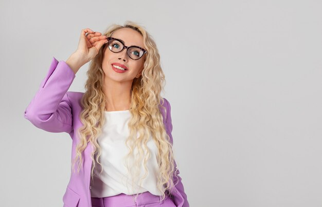 Portrait of a pretty modern beautiful woman in glasses, touching-eyed glasses, smiling amiably and enthusiastically,