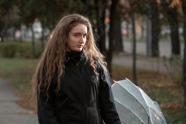 秋の公園で美しい少女の写真、長いウェーブのかかった髪を持つかなり物思いにふける若い女性の肖像画