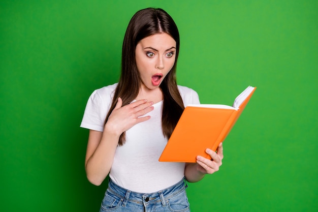 Portrait of pretty shocked brunette hair young lady look book wear casual t-shirt isolated on green background