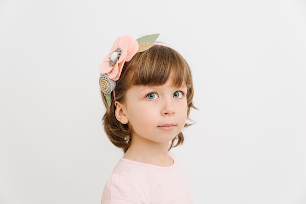 Portrait of pretty small girl with blue eyes and felt flowers hoop Childhood and joy concept