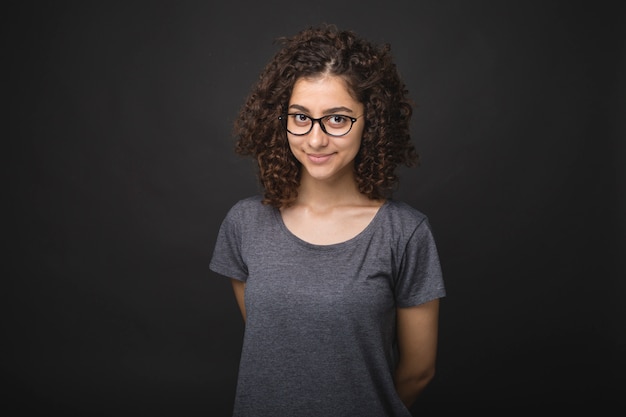 Portrait of a pretty smiling brunette woman in glasses of mixed race on a black . 