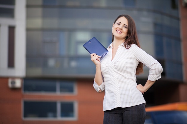 Portrait of pretty student or businesswoman in smart casual using digital tablet outdoors