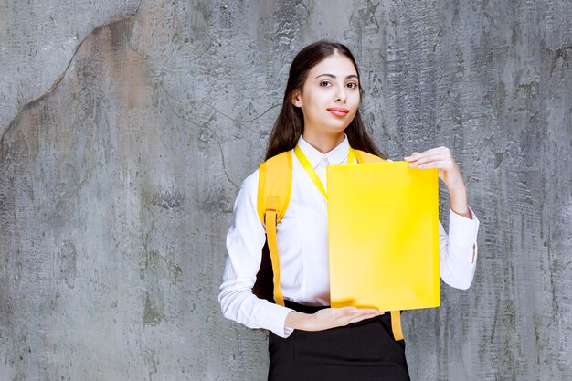 Portrait of pretty student with yellow notebook posing to camera. High quality photo