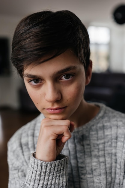 Photo portrait of a pretty teenager sitting on the chair indoors