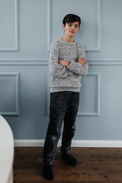 Portrait of a pretty teenager standing near the wall indoors