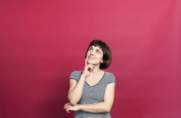 Portrait of pretty thirty-year-old woman with short hair in striped dress on  pink background