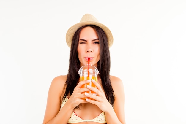 Portrait of pretty tourist in summer hat drinking orange juice