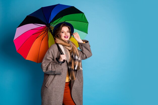 portrait of pretty traveler lady hold colorful parasol walking down street wear stylish casual long grey coat jumper orange pants hat plaid scarf .