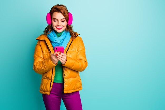 かわいい旅行者の女性の肖像画は、電話検索ルックマップユーザーナビゲーションシステムを保持し、流行のカジュアルな黄色のオーバーコートスカーフ紫のズボンを着用します。