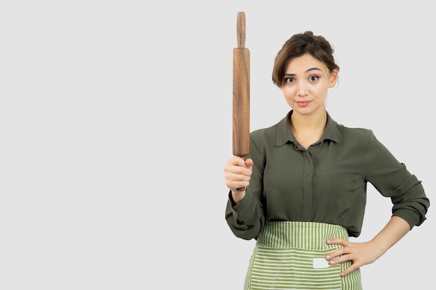 Portrait of pretty woman in apron holding a rolling pin . High quality photo