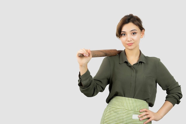 Portrait of pretty woman in apron holding a rolling pin . High quality photo
