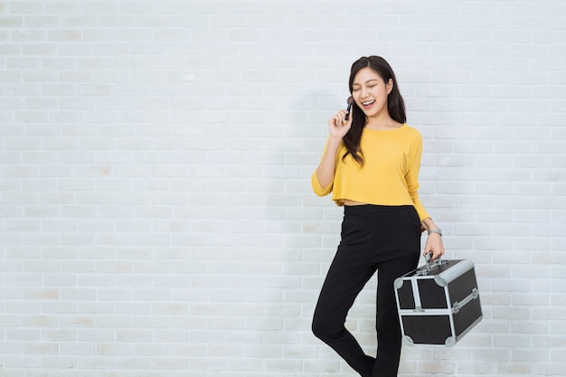 Portrait of pretty woman carrying a makeup brush and case