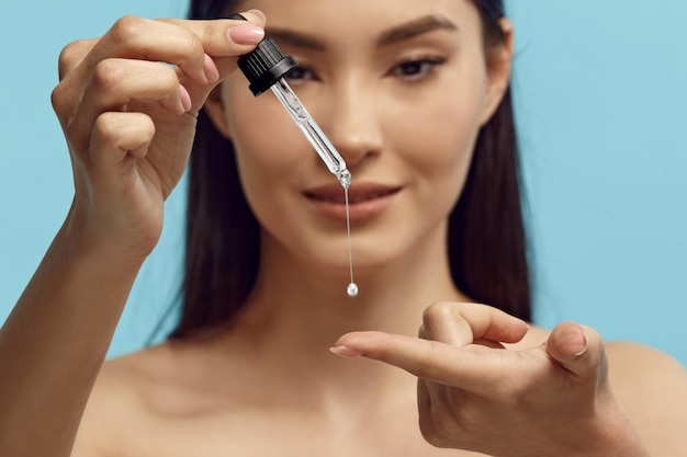 Portrait of pretty woman dripping serum on her finger