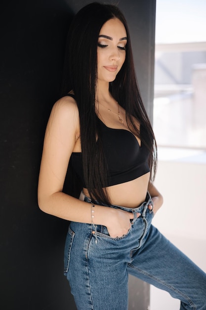 예쁜 여자의 초상화는 맨발로 데님과 흰색 셔츠를 입은 섹시한 여자 스튜디오에서 포토세션을 가지고 있습니다.
