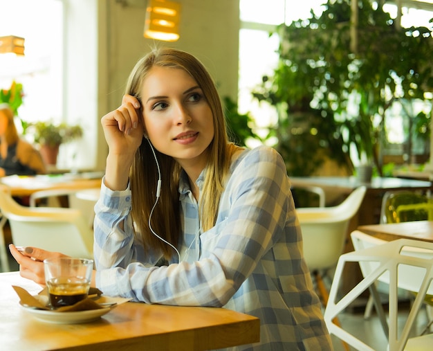 Portrait of pretty woman listening music and holding mobile phon