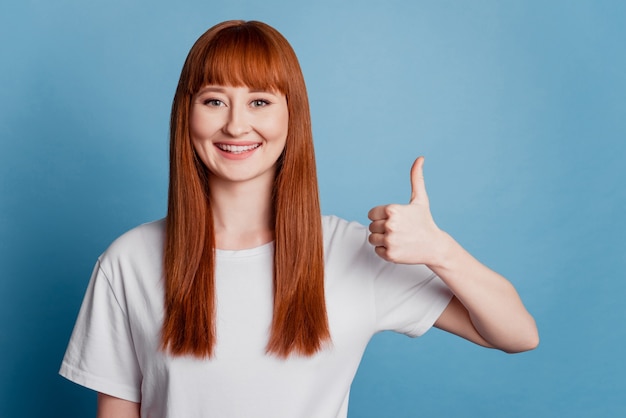 Portrait of a pretty woman showing thumbs up over blue background