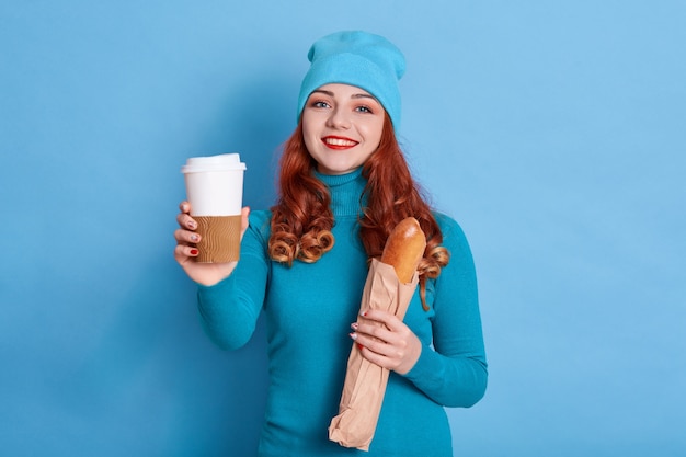 Portrait of pretty woman wearing casual sweater and cap, smiling sincerely