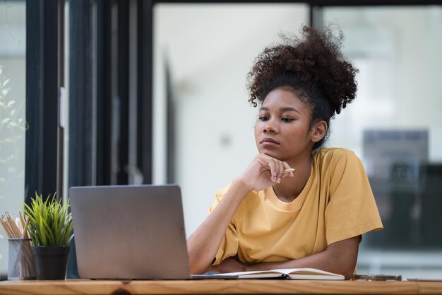 portrait of a pretty young black woman a serious working on a laptop sitting on the desk