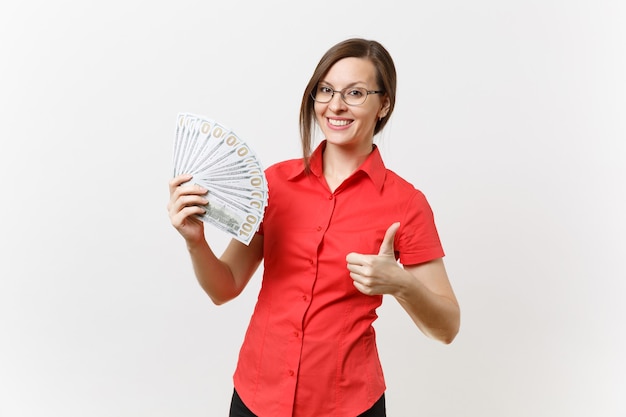 Portrait of pretty young business teacher woman in red shirt skirt glasses holding bundle lots of dollars, cash money isolated on white background. Education teaching in high school university concept