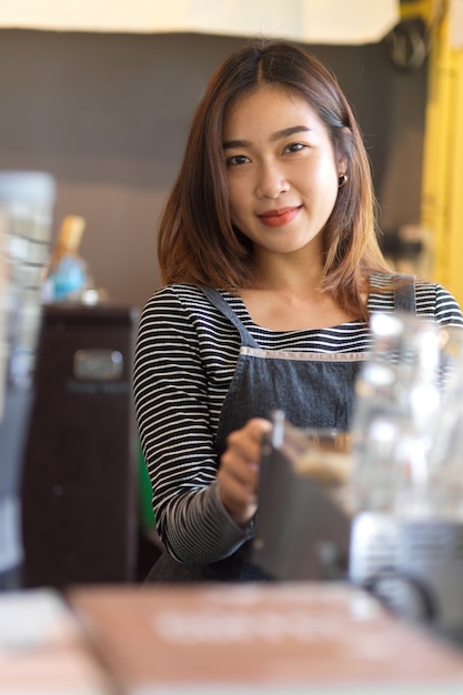 コーヒーショップ、カフェのスタッフ、ビジネスオーナーのカメラに微笑むかなり若い女性バリスタの肖像画