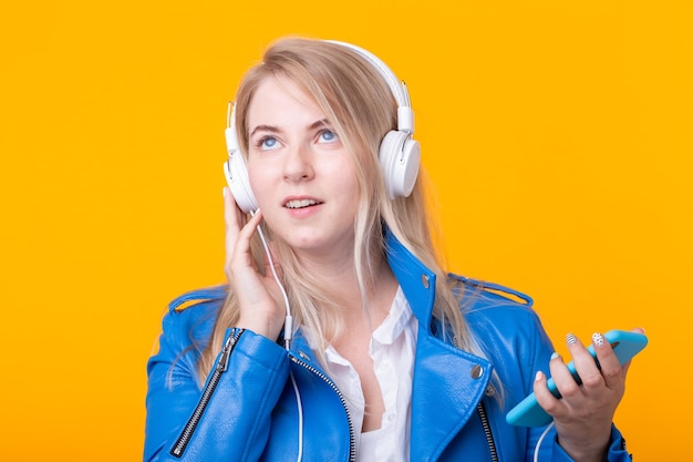 Portrait of pretty young girl blonde female student holding smartphone with blue leather jacket